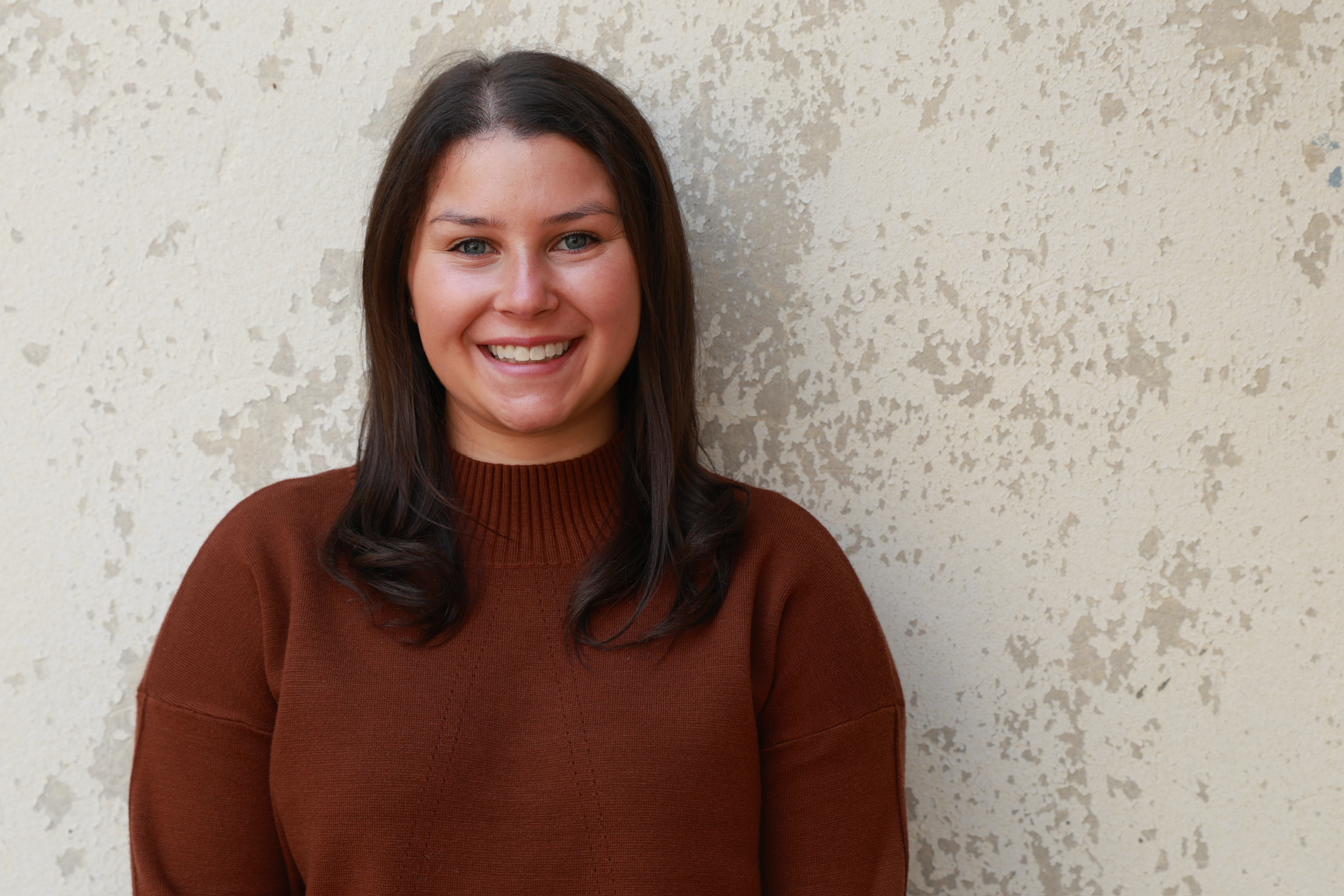 Hannah, founder and head coach of Precision Rally, smiling in a brown sweater